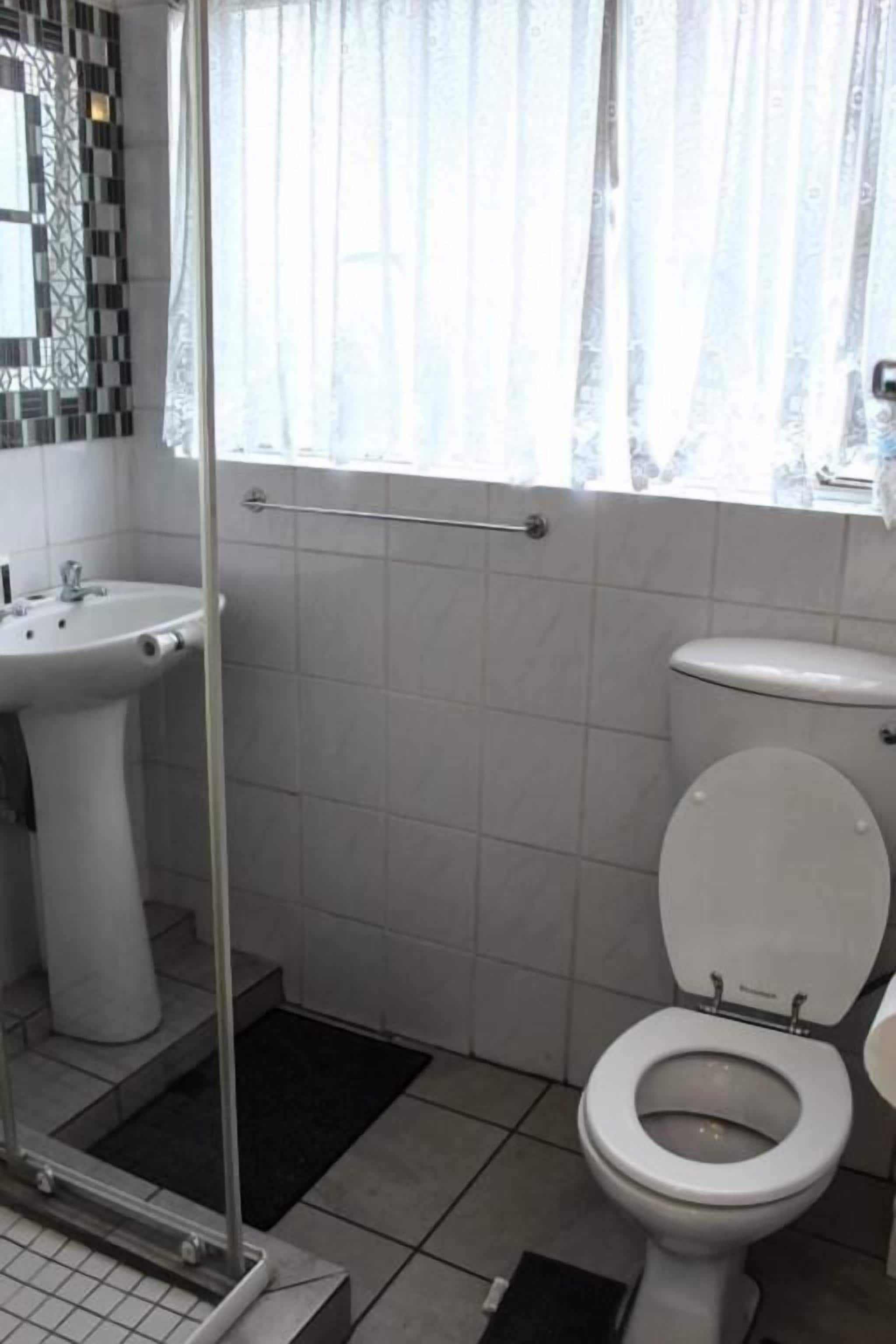 A bathroom with a toilet, sink, and a glass shower enclosure.