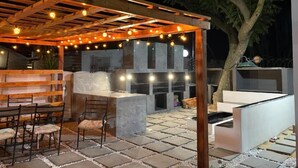 Un espace extérieur aménagé en terrasse, avec une pergola, des sièges et un comptoir de bar.