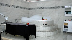 Une salle de spa équipée d’une table de massage, d’une petite fontaine et d’un miroir.