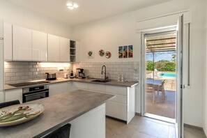 A modern kitchen with white cabinets, a countertop, and a view of an outdoor pool area.