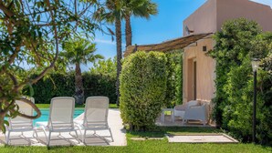 A poolside area with lounge chairs and a building with a pergola. - Villa Bouganville by Wonderful Italy (Syracuse)