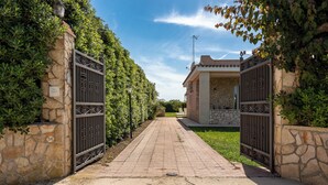 A paved pathway leading to a gated entrance with stone walls and a clear sky. - Villa Bouganville by Wonderful Italy (Syracuse)