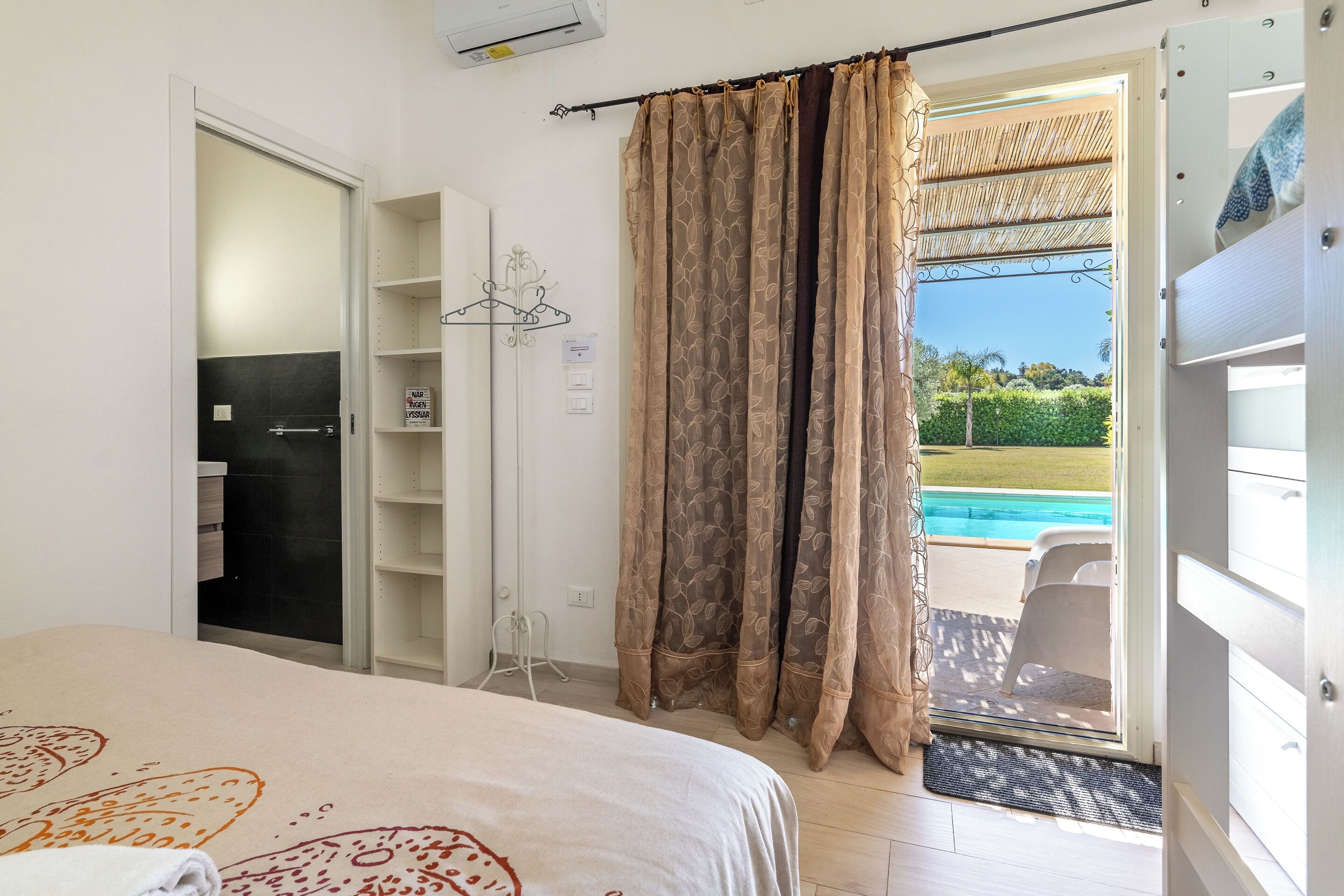 Un dormitorio con cama, armario, baño y vistas a una piscina.
