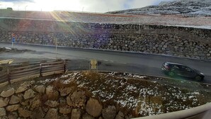 Un muro di pietra con una ringhiera metallica, una strada con un'auto e una scala di pietra.