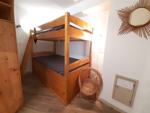 A bunk bed with a ladder, a wicker basket, and a wall-mounted mirror.