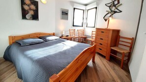 Una camera da letto con un letto, una scrivania, sedie, una cassettiera e un quadro astratto appeso al muro.