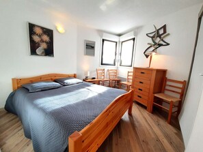 Un dormitorio con una cama, un escritorio, sillas, un aparador y una obra de arte abstracto colgada en la pared.
