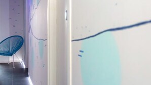 A hallway with a blue chair, white walls, and a door.