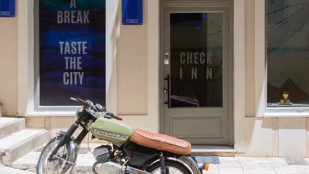 A motorcycle parked in front of a building with arched windows and a sign that reads "CHECK INN".
