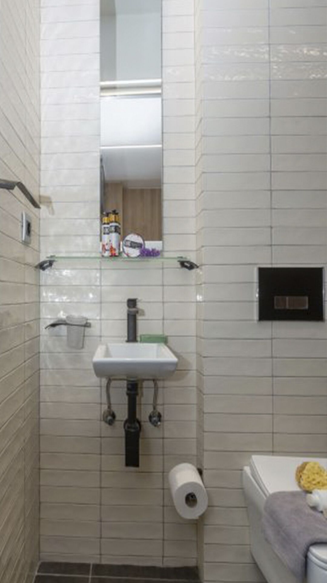 Un baño con lavamanos blanco, espejo, inodoro y un perchero para toallas.