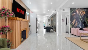Een modern interieur met een Netflix-bord, een houten wand, een eethoek en een woonkamer met een bank.