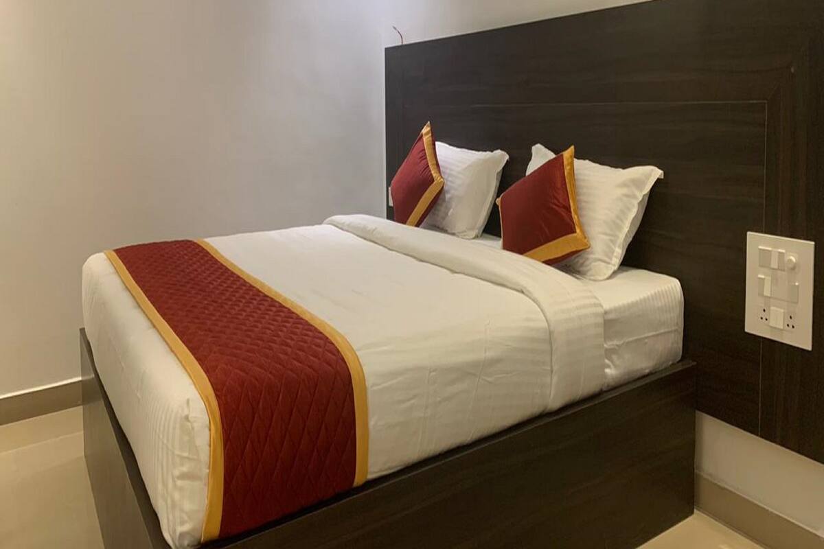 A hotel room with a bed, a dark headboard, and a white wall.