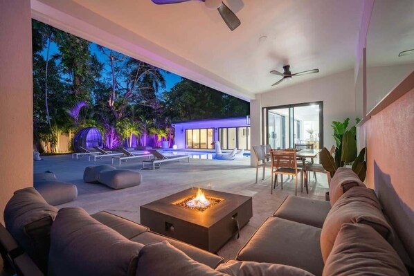 An outdoor living area with a fire pit, lounge chairs, and a dining table. - Luxury Villa Azure with Heated Pool 20min to Beach (Miami)