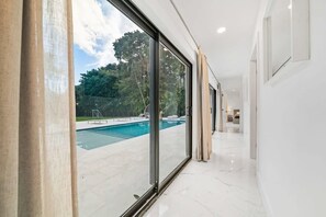 Un intérieur moderne avec une piscine visible à travers de grandes portes vitrées.