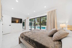 Une chambre moderne avec un grand lit, une télévision et une vue sur une piscine.