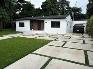 A modern house with a paved driveway and a black truck parked in the driveway.