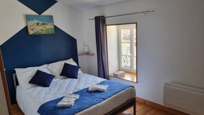 Ein Schlafzimmer mit Bett, einem Bild, einem Fenster und einer Heizung.