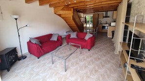 Una sala de estar acogedora con un sofá rojo, una lámpara de pie y un techo de madera.