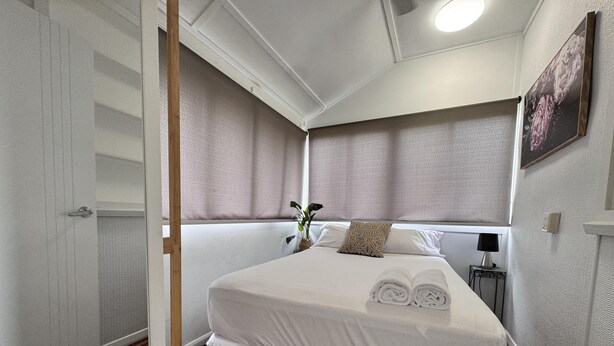 A neatly arranged bedroom with a bed, bedside table, and a nightstand.