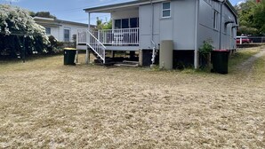 A single-story house with a front porch, a small staircase, and a fenced yard.