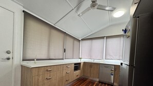 A compact kitchen with wooden cabinets, a built-in dishwasher, and a ceiling fan.