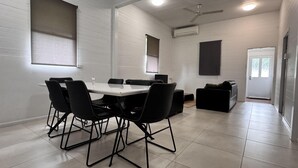 A modern dining area with a white table and black chairs, a ceiling fan, and an air conditioning unit.