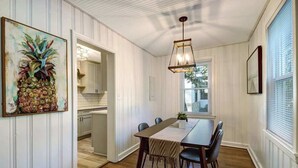 Ein Essbereich mit Holztisch, Stühlen, einer Pendelleuchte und einem Fenster mit Jalousien.