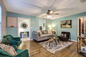 A living room with a sofa, armchair, coffee table, and a ceiling fan.
