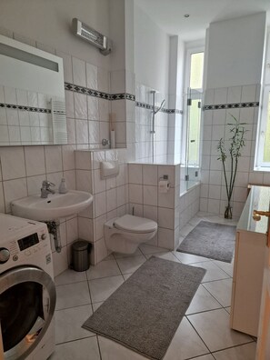 Een moderne badkamer met een wastafel, toilet en wasmachine.