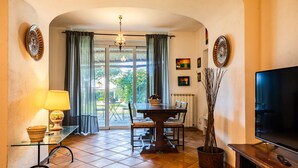 A dining area with a glass table, chairs, a lamp, and a television. - Villa Marghe - Sea View Rooms (Massa Lubrense)
