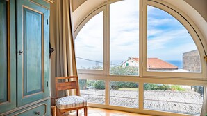 A room with a large arched window, a wooden chair, and a teal-colored cabinet. - Villa Marghe - Sea View Rooms (Massa Lubrense)