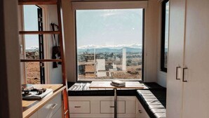 Een hoekappartement met raam, een inbouwkruk en een kitchenette.