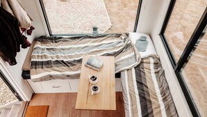 Een knus ingerichte kamer met een bed, een klein tafeltje en een raam.