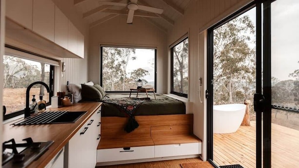 A compact room with a bed, a sink, and a large window.