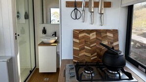 A compact kitchen with a gas stove, a wooden herringbone backsplash, and a window.