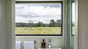 A bathroom with a window view of a grassy field and trees. - Tiny Charlotte - Southern Tablelands (Dalton)