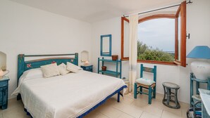 Una camera da letto con un letto, una finestra, una sedia, un comodino e una lampada.