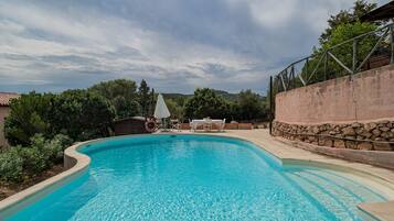 Relax by the serene pool surrounded by lush greenery and a stone wall.