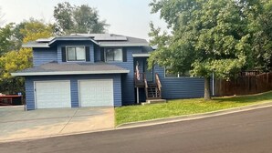 A two-story house with a garage, a small porch, and a tree in the yard. - Family Flat for 8 (Auburn)