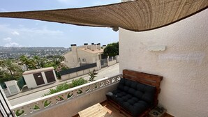 A balcony with a wooden bench, a small table, and potted plants. - Casa David: Relax Cerca de la Playa (Teulada)