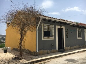 A building with a yellow facade, a black door, and a window with metal bars. - Casa David: Relax Cerca de la Playa (Teulada)