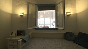 A bedroom with a bed, a nightstand, a window with open shutters, and wall-mounted lights. - Casa David: Relax Cerca de la Playa (Teulada)