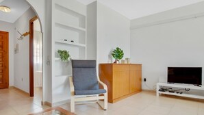 Un salon moderne avec un fauteuil gris, un meuble en bois et un téléviseur à écran plat.