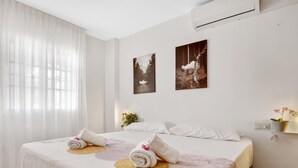 Une chambre d’hôtel avec un lit, deux climatiseurs fixés au mur et deux tableaux encadrés.