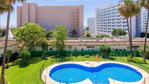 Un hôtel doté d’une piscine, entouré de palmiers et surplombant un ciel d’un bleu limpide.