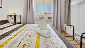 Une chambre d’hôtel avec un lit, une table de chevet avec une lampe, une fenêtre avec des rideaux et une vue sur l’extérieur.