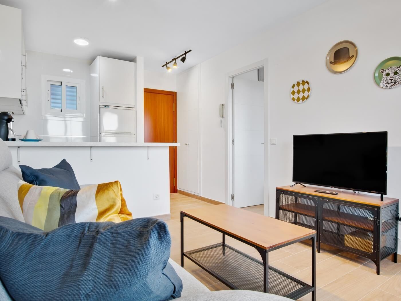 Una sala de estar moderna con un sofá, una mesa de centro y un televisor sobre un mueble.