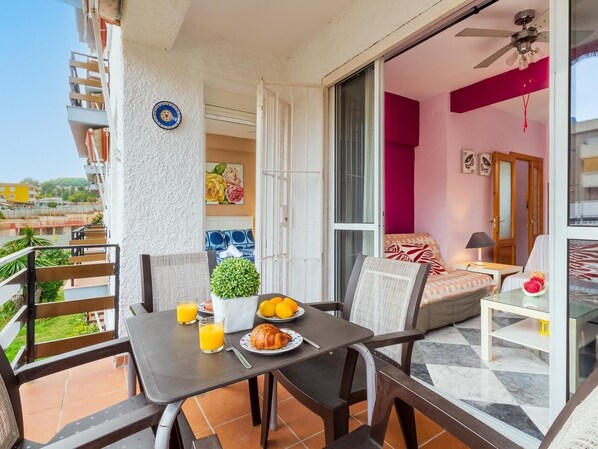 A balcony with a table set for breakfast, a chair, and a sofa.