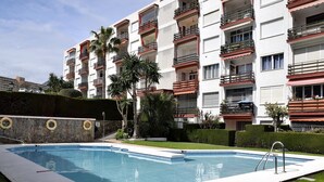 A swimming pool with a stone wall and palm trees. - Sol Montemar 23 - Swimming Pool, Parking, 200m from the beach (Torremolinos)