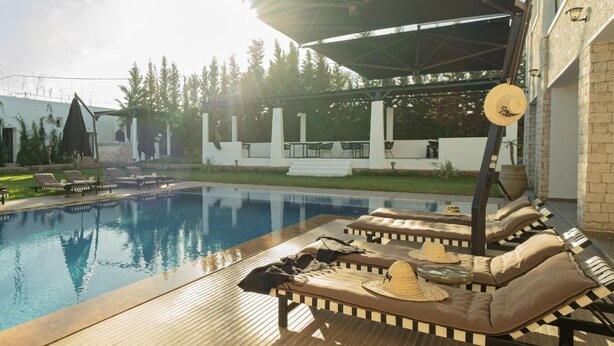 A poolside area with lounge chairs and a covered seating area. - Cavanna Lodge (Ounagha)